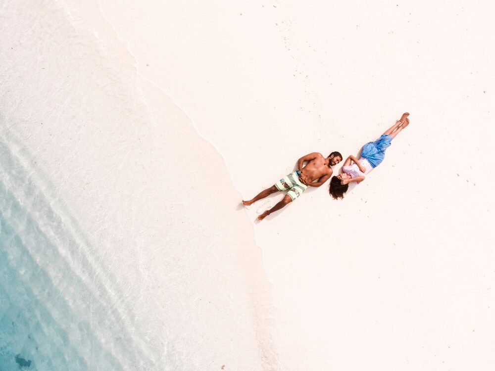 Mann in Badehose und Frau in Shirt und kurzer Hose liegen am Strand