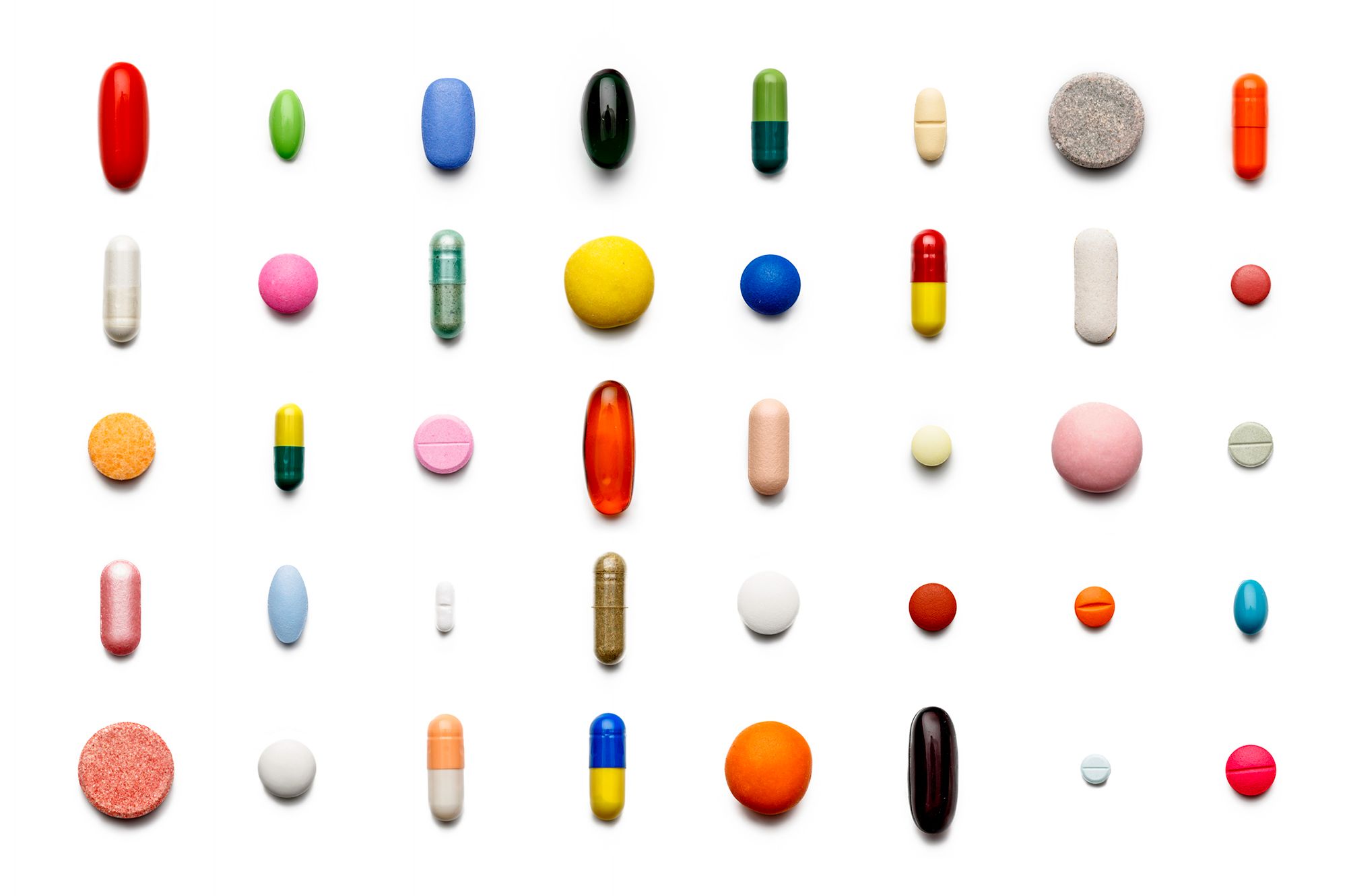 Viele bunte Pillen die geordnet auf einem weißen Hintergrund liegen