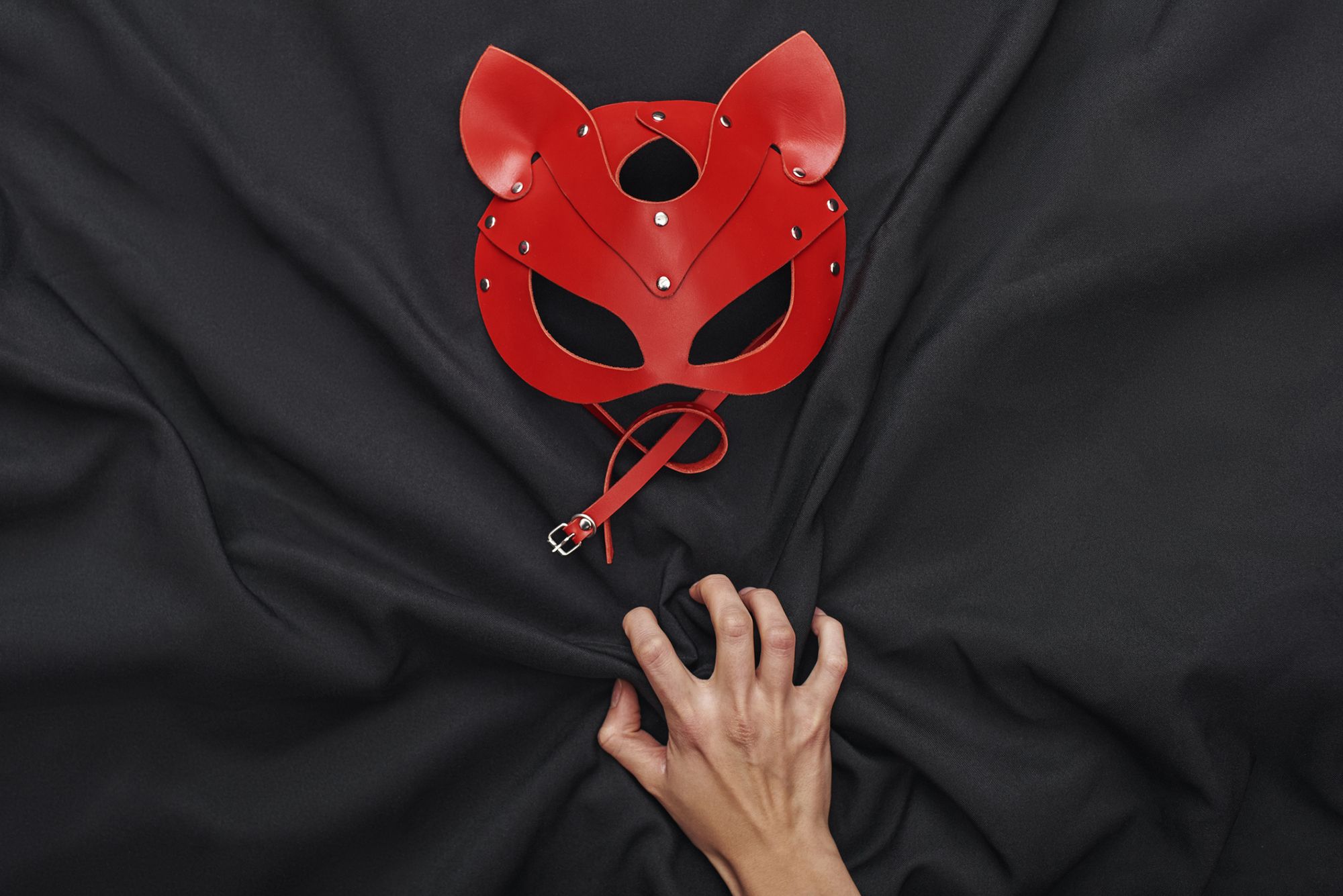 Rote Tiermaske aus Leder auf schwarzem Stoff-Hintergund