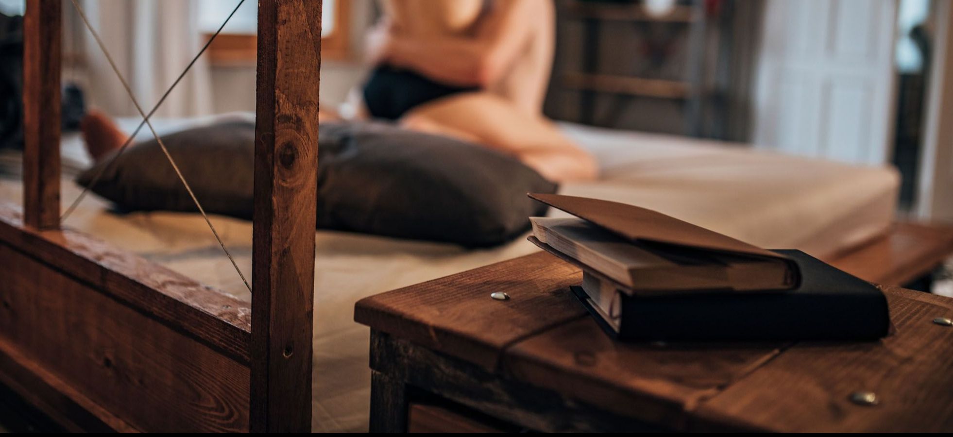 Bücher liegen auf einem Hocker, im Hintergrund hat ein Paar Sex