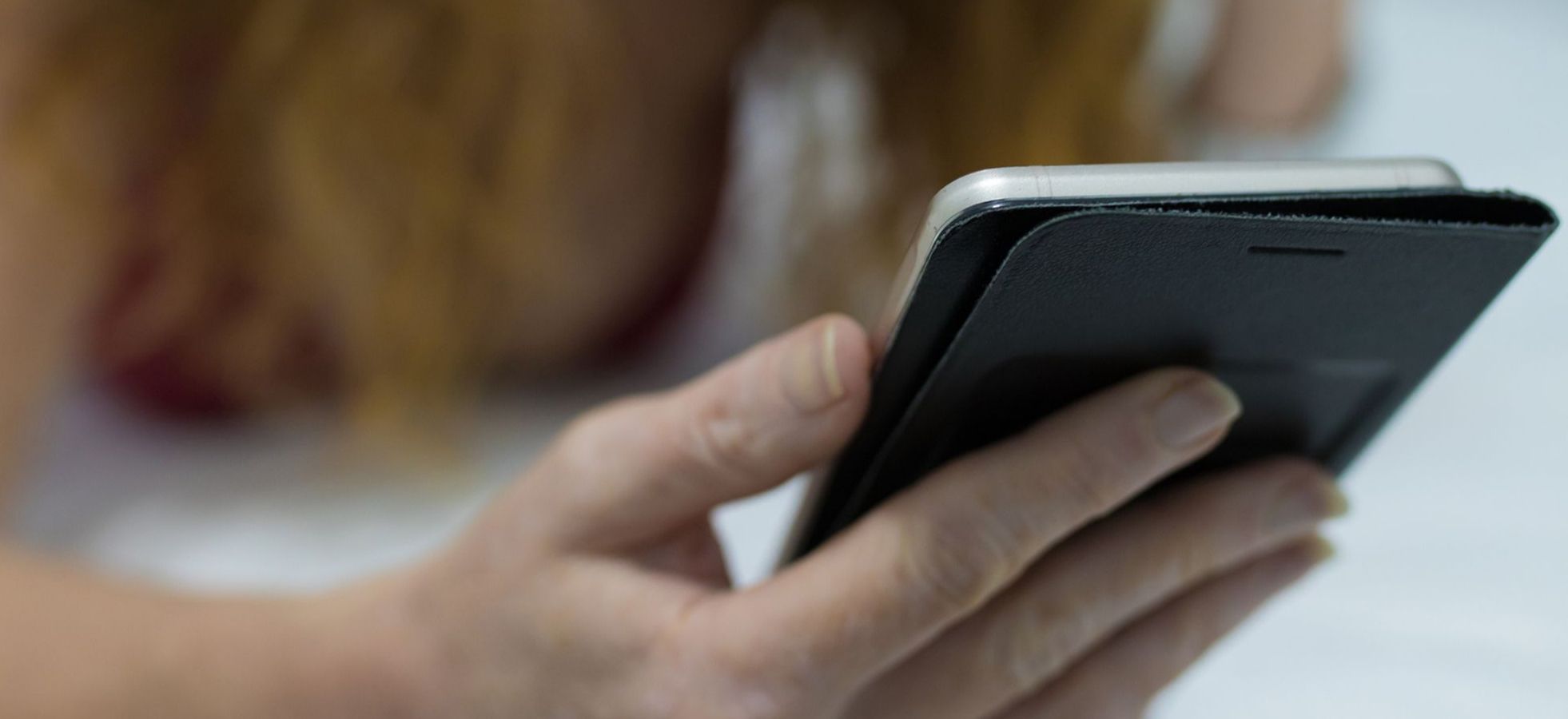 Frau lieht auf dem Bauch und hält ihr Handy in der Hand