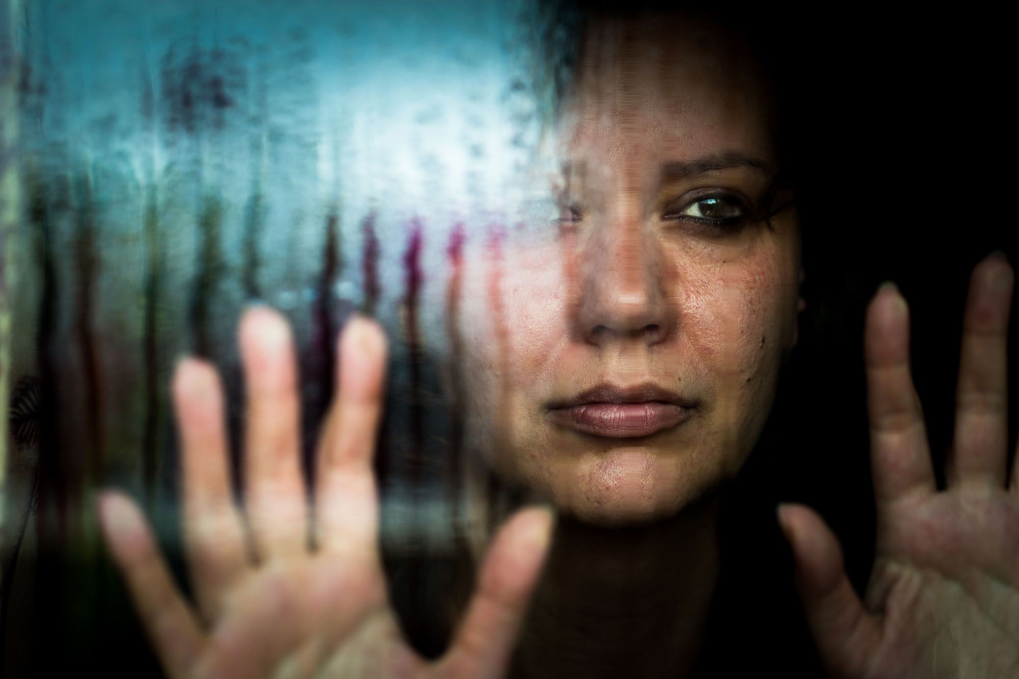 Weinende Frau steht am Fenster