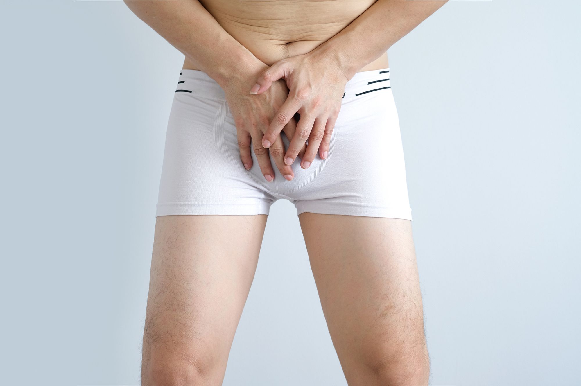 Mann in Boxershorts hält die Hände vor sein Geschlecht