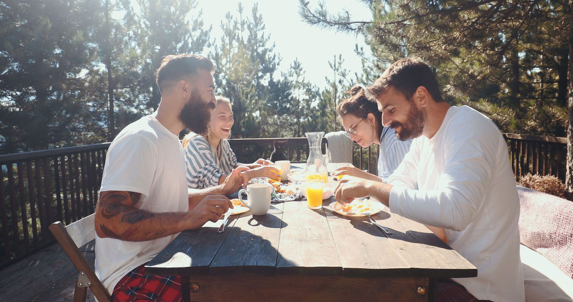 2 Paare sitzen gemeinsam an einem Tisch und essen