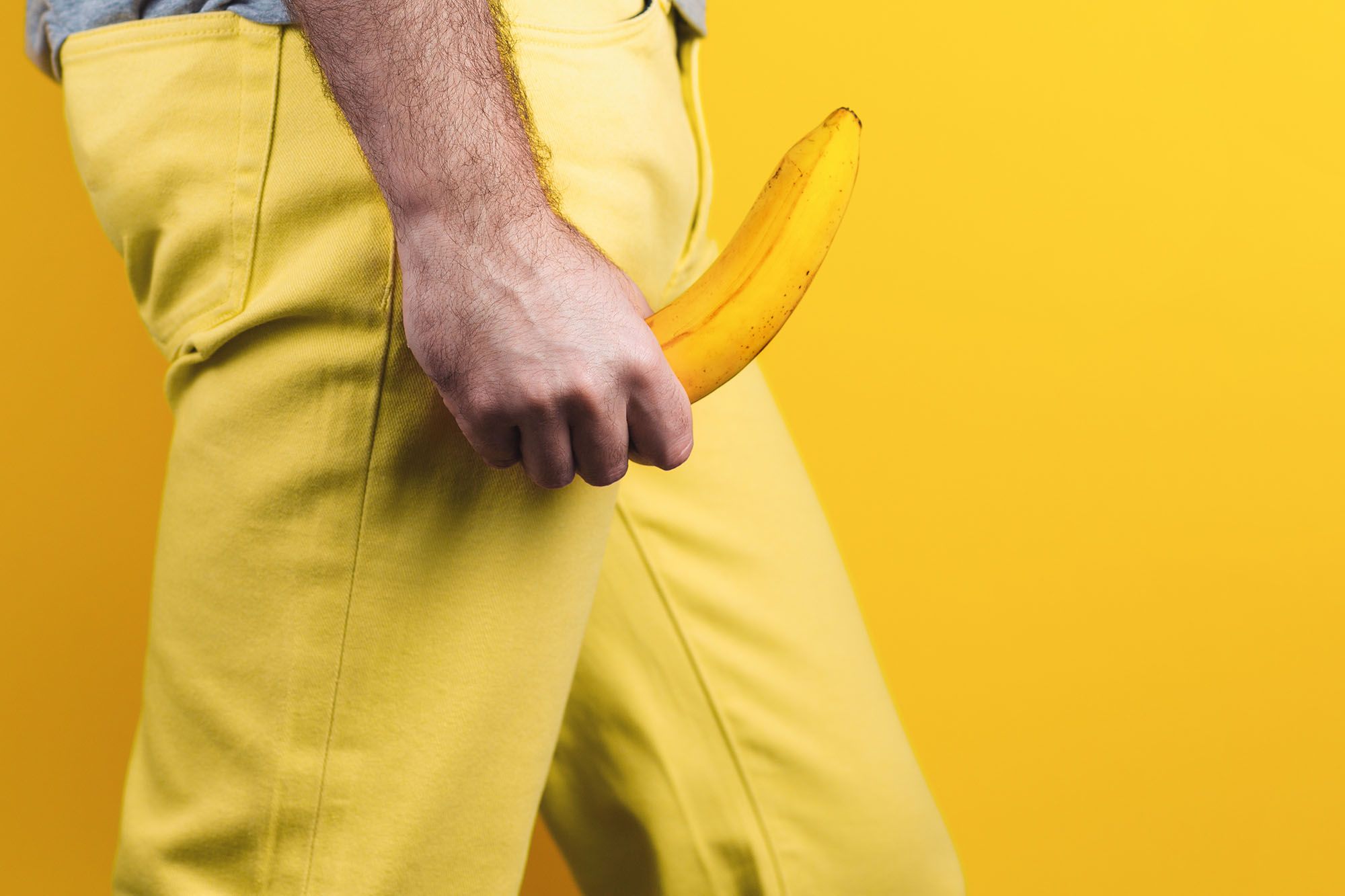 Penis in Unterhose - Abbildung eines männlichen, bekleideten Unterkörpers, welcher mit einer Banane als Penis-Attrappe einen erigierten Penis andeutet.