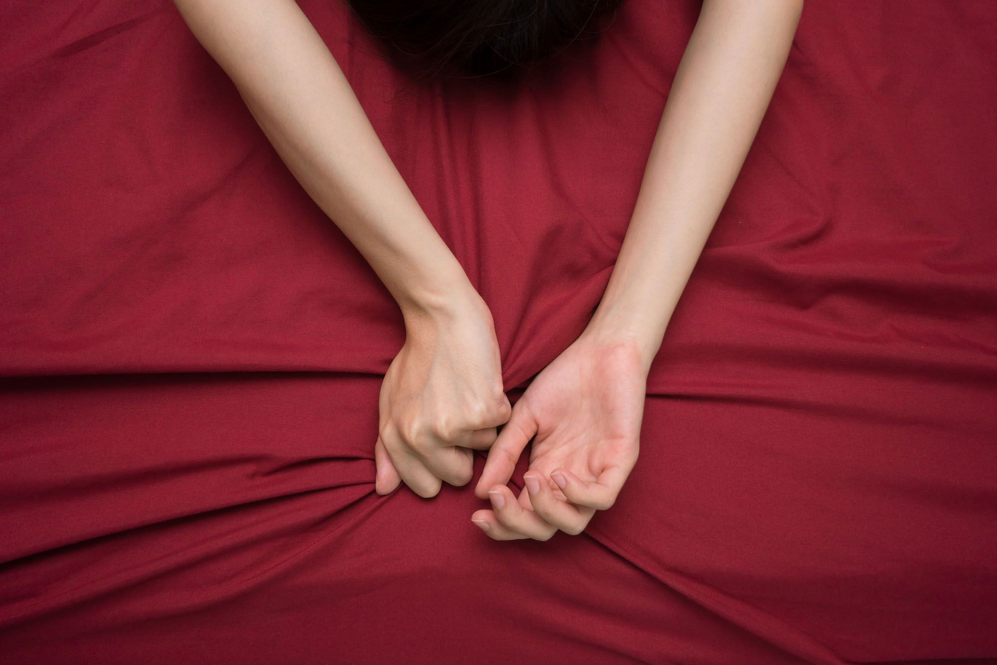 Hände und Arme einer Frau, die ausgestreckt auf dem Bett liegen
