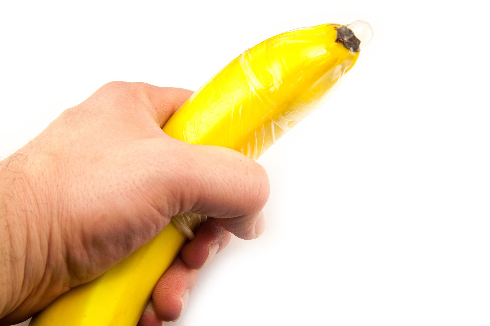 Mann hält eine Banane in der Hand, über die ein Kondom gestülpt ist
