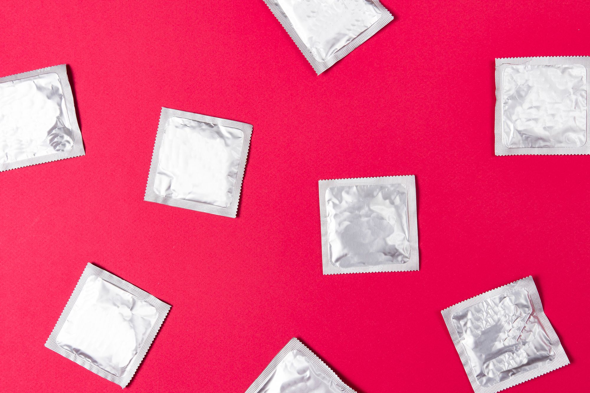 Silberne Kondomverpackungen auf rotem Hintergrund