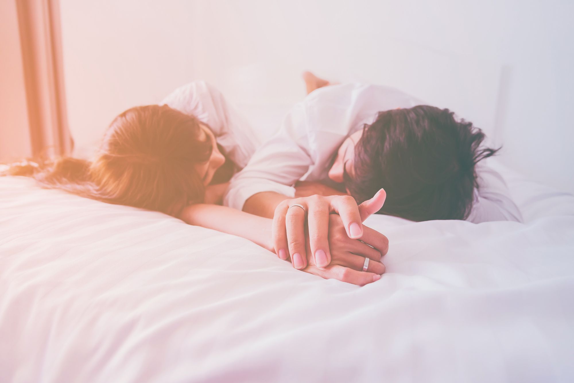 Mann und Frau halten Händchen im Bett