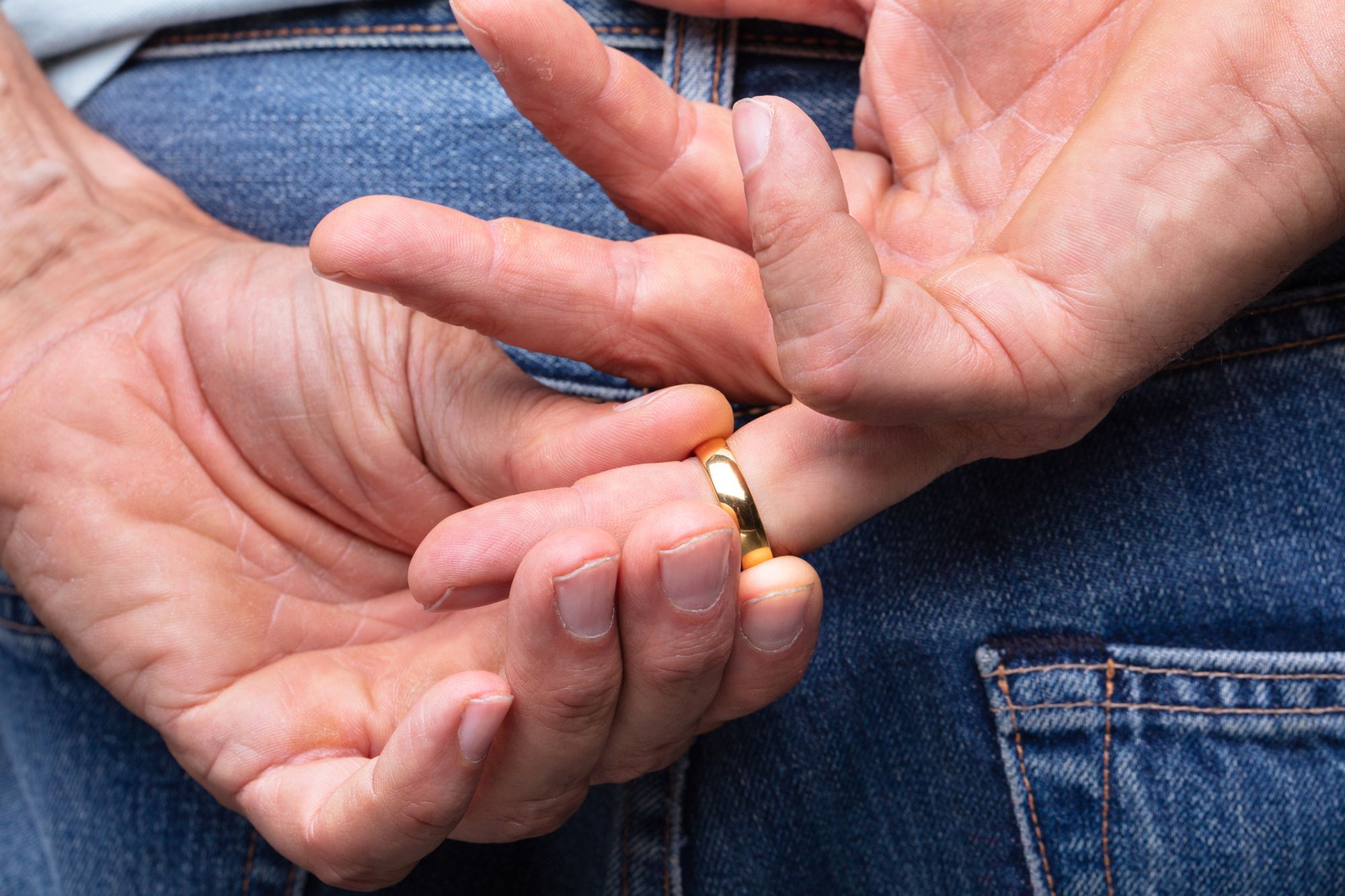 Mann zieht hinter seinem Rücken den Ehering vom Finger