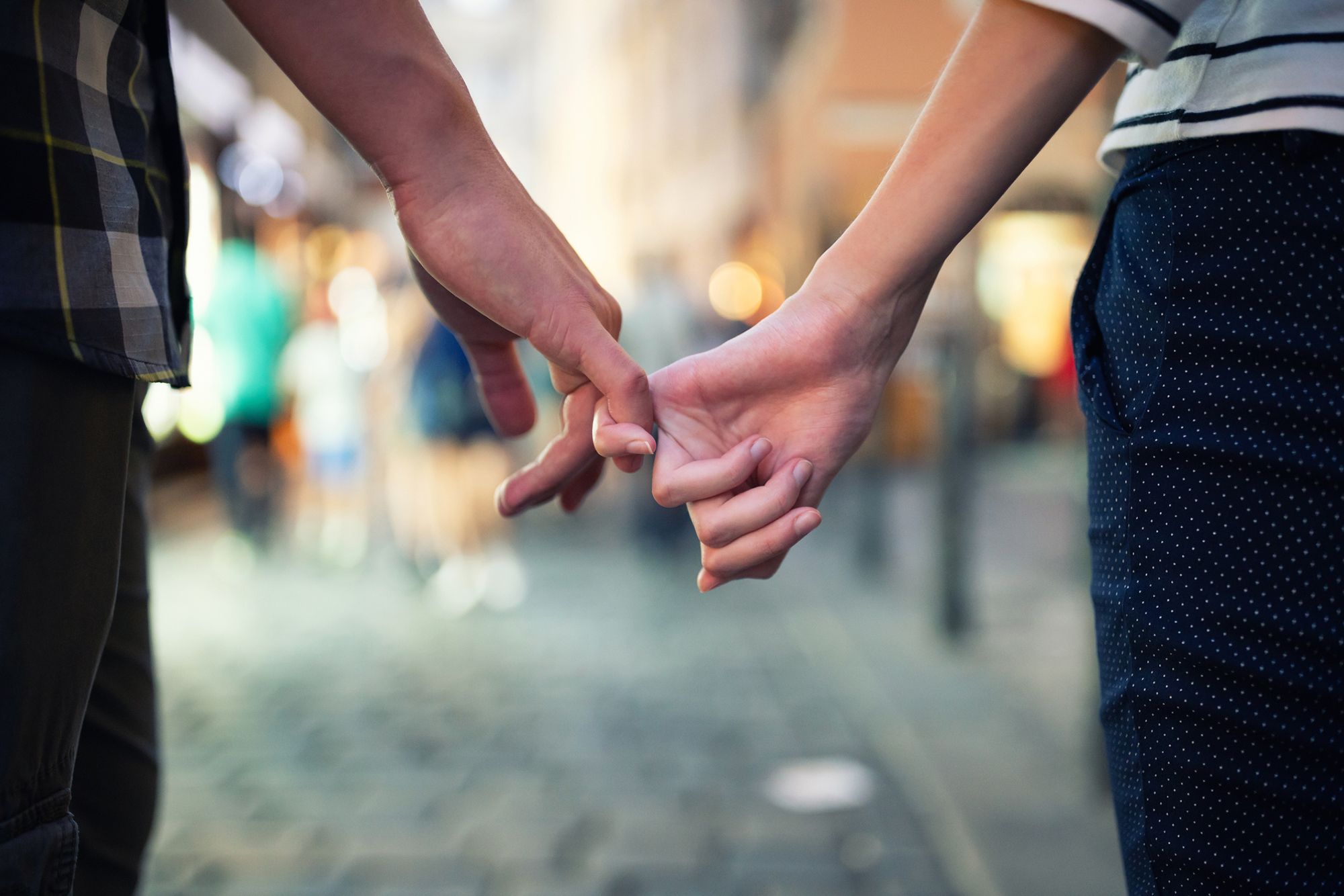 Frau und Mann laufen mit verschränkten Fingern durch die Stadt