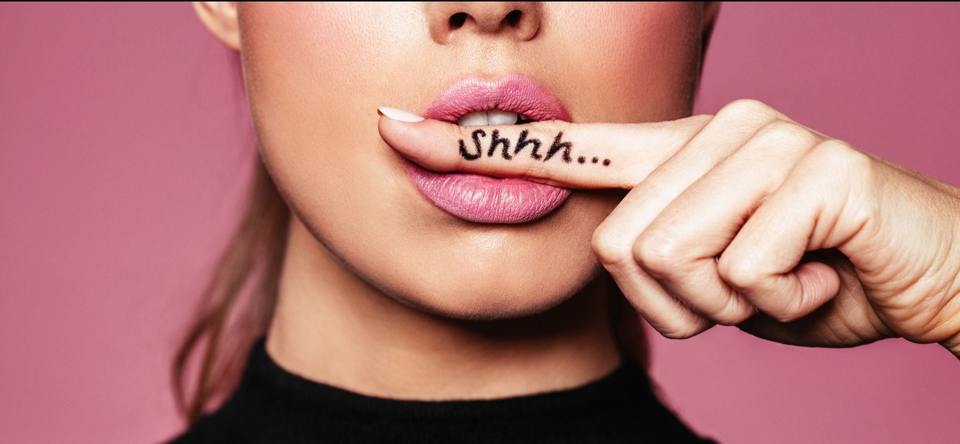 Frau hält einen Zeigefinger vor dem Mund, auf dem "Shhh..." geschrieben steht