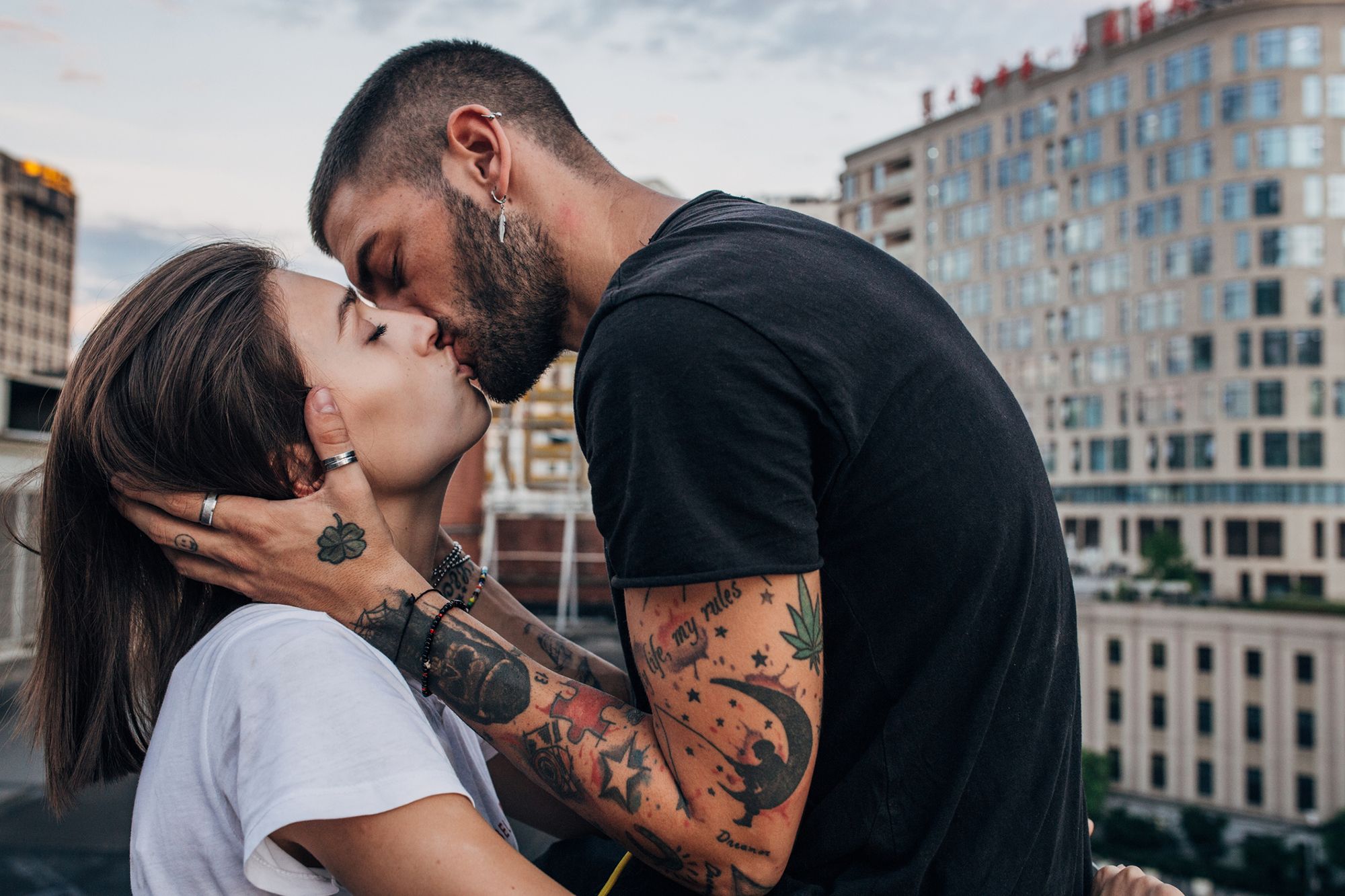 Tätowierter Mann küsst leidenschaftlich eine Frau 