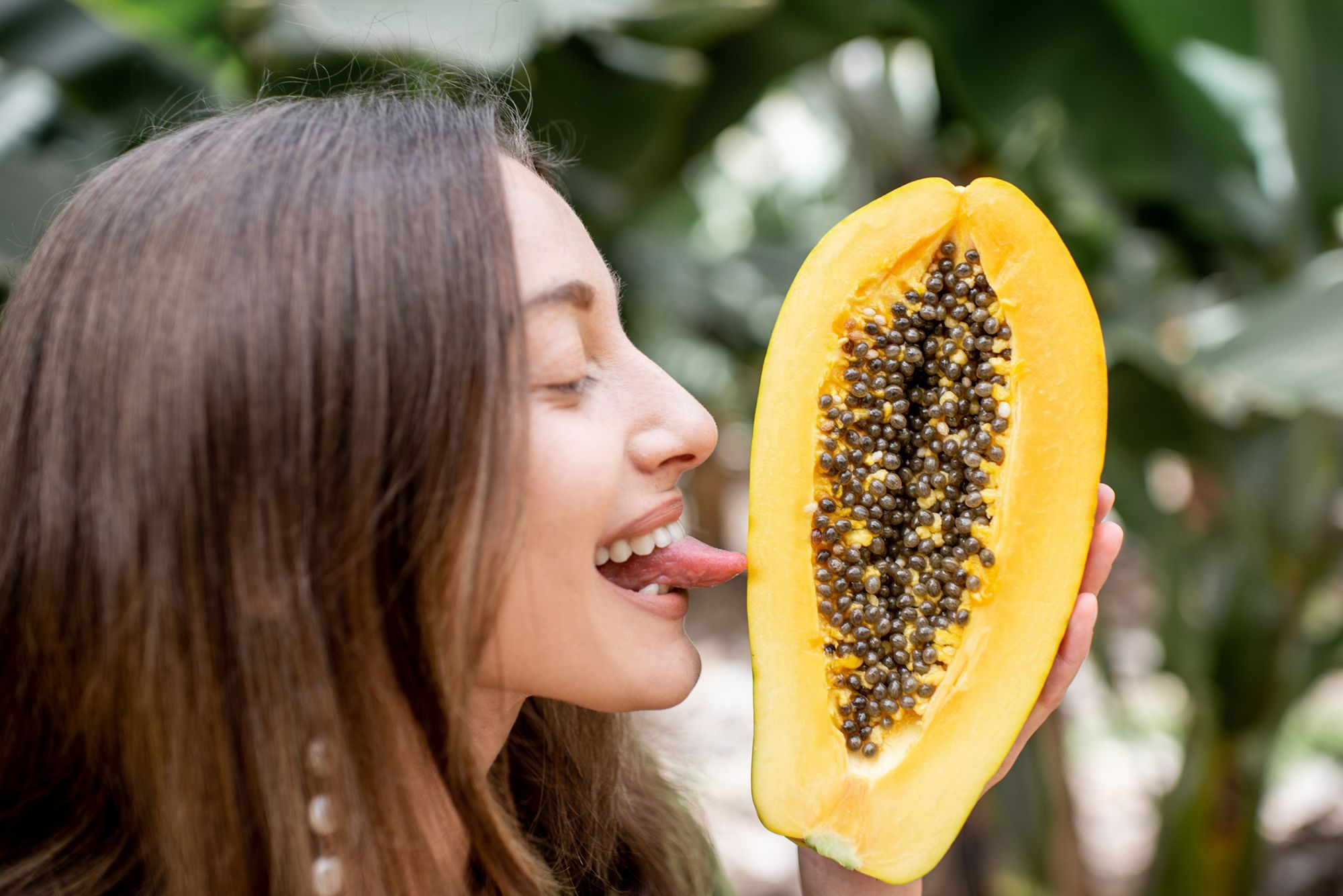 Frau leckt an einer halben Papaya