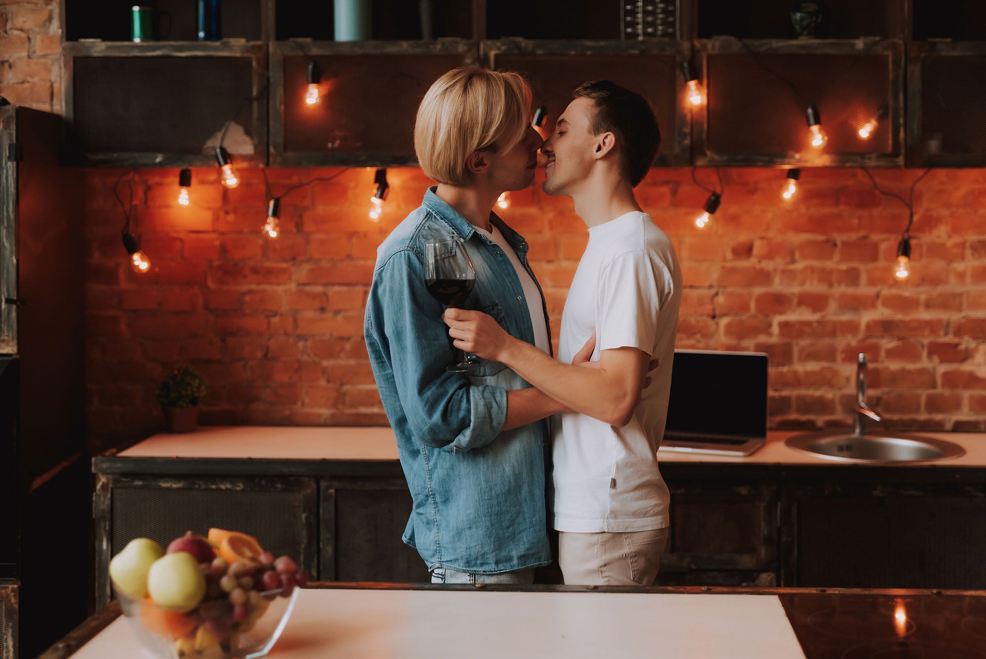 Zwei Männer, die in einer Küche stehen und sich küssen