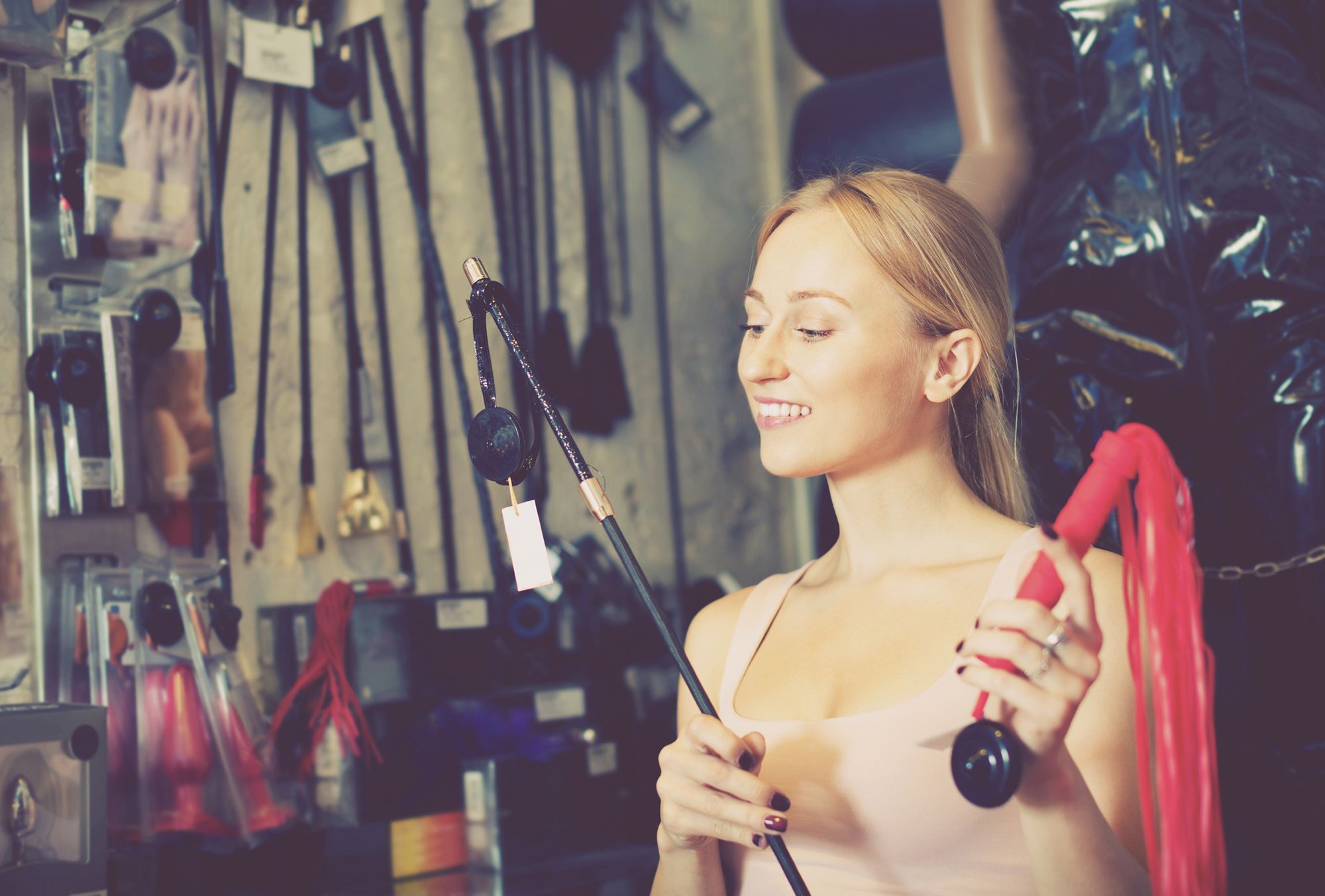 Frau steht in einem Laden mit verschiedenen BDSM-Toys
