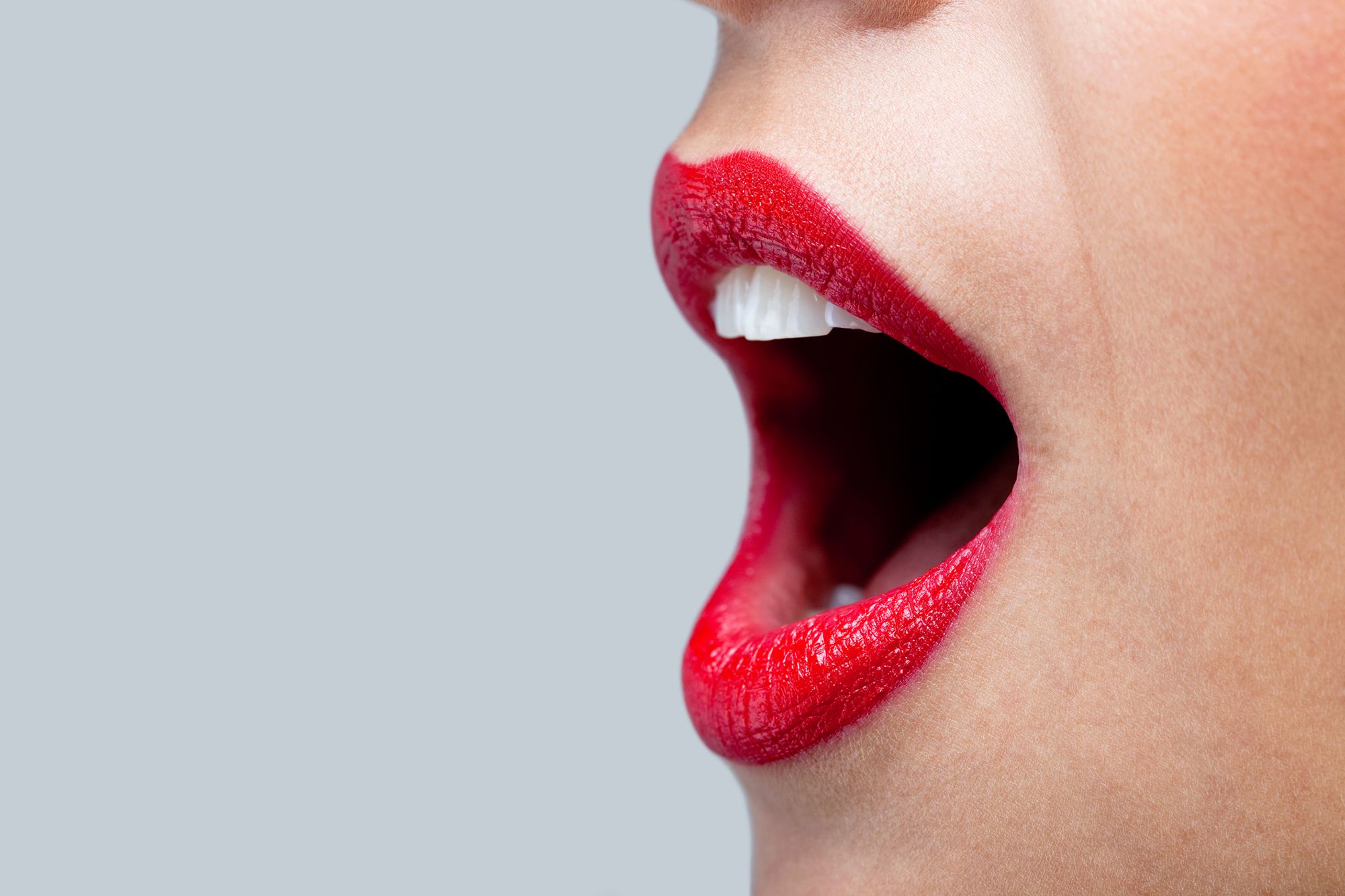 Nahaufnahme einer Frau mit rotem Lippenstift und geöffnetem Mund