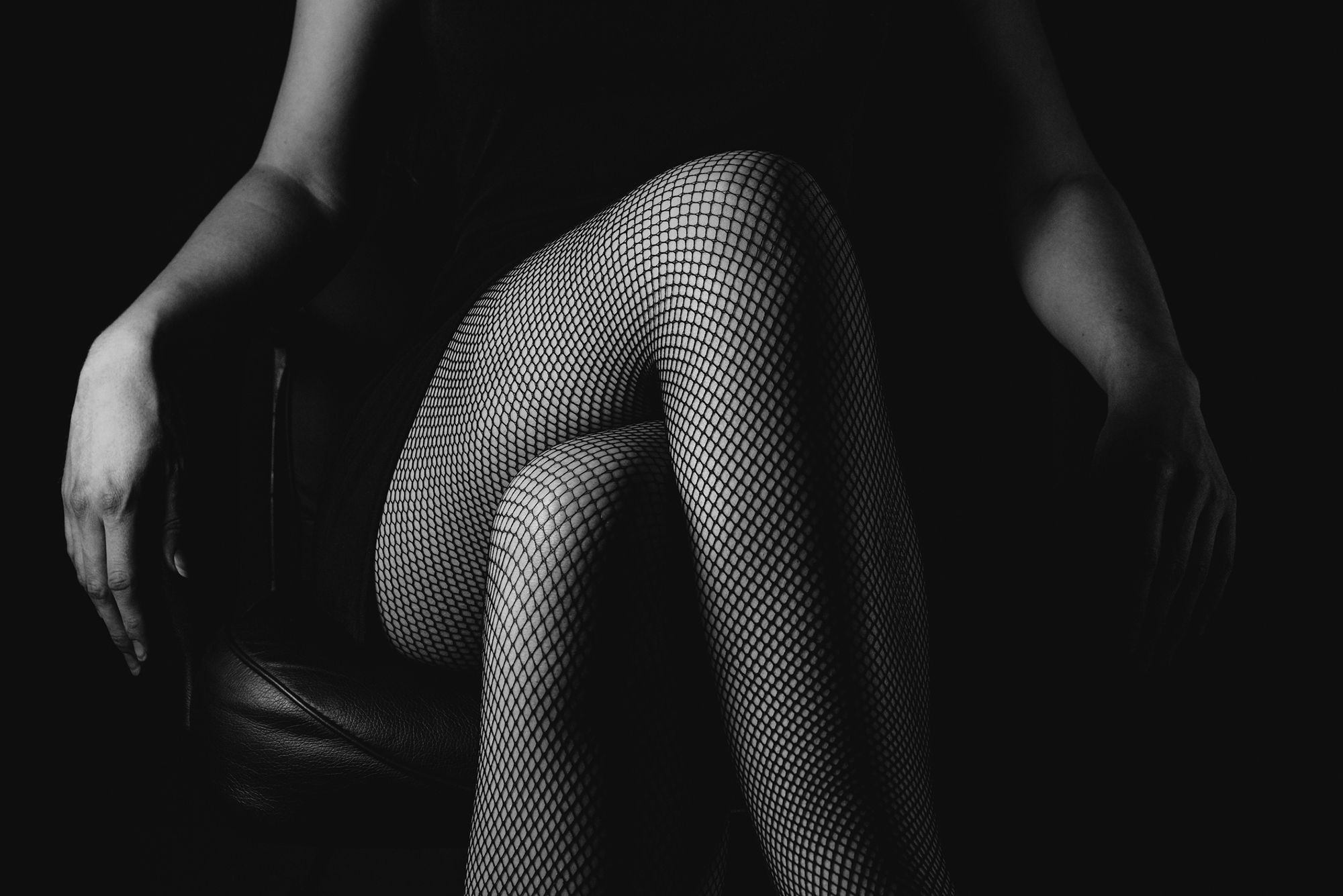 Frau in Netzstrumpfhose mit überschlagenen Beinen
