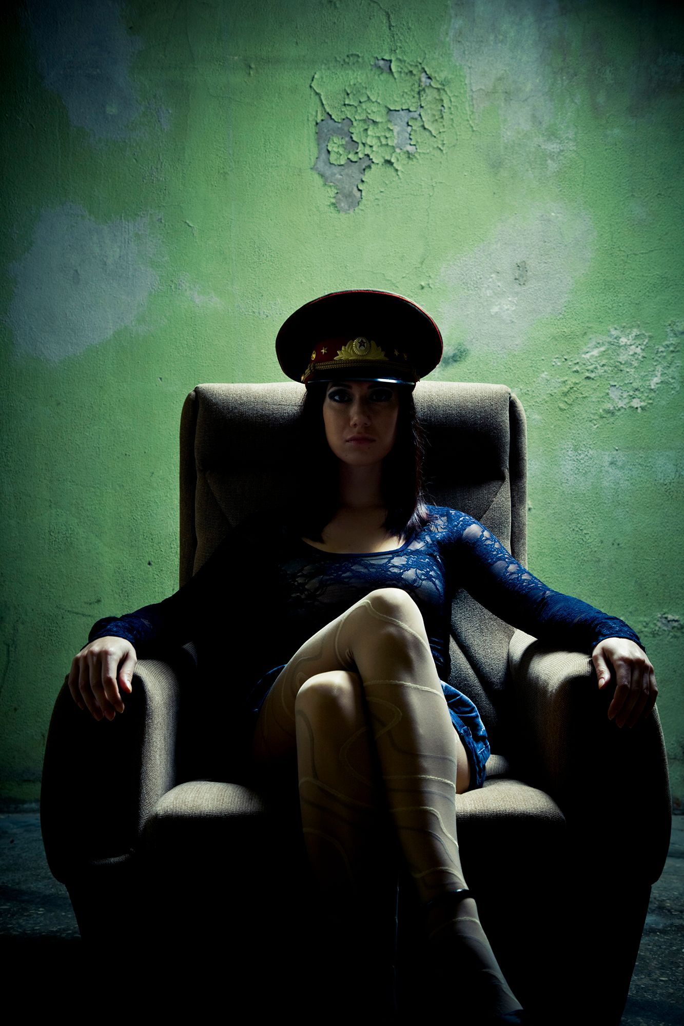 Domina Telefonsex - Abbildung einer Frau mit Polizei-Hut, welche mit überschlagenen Beinen auf einem Sessel sitzt.