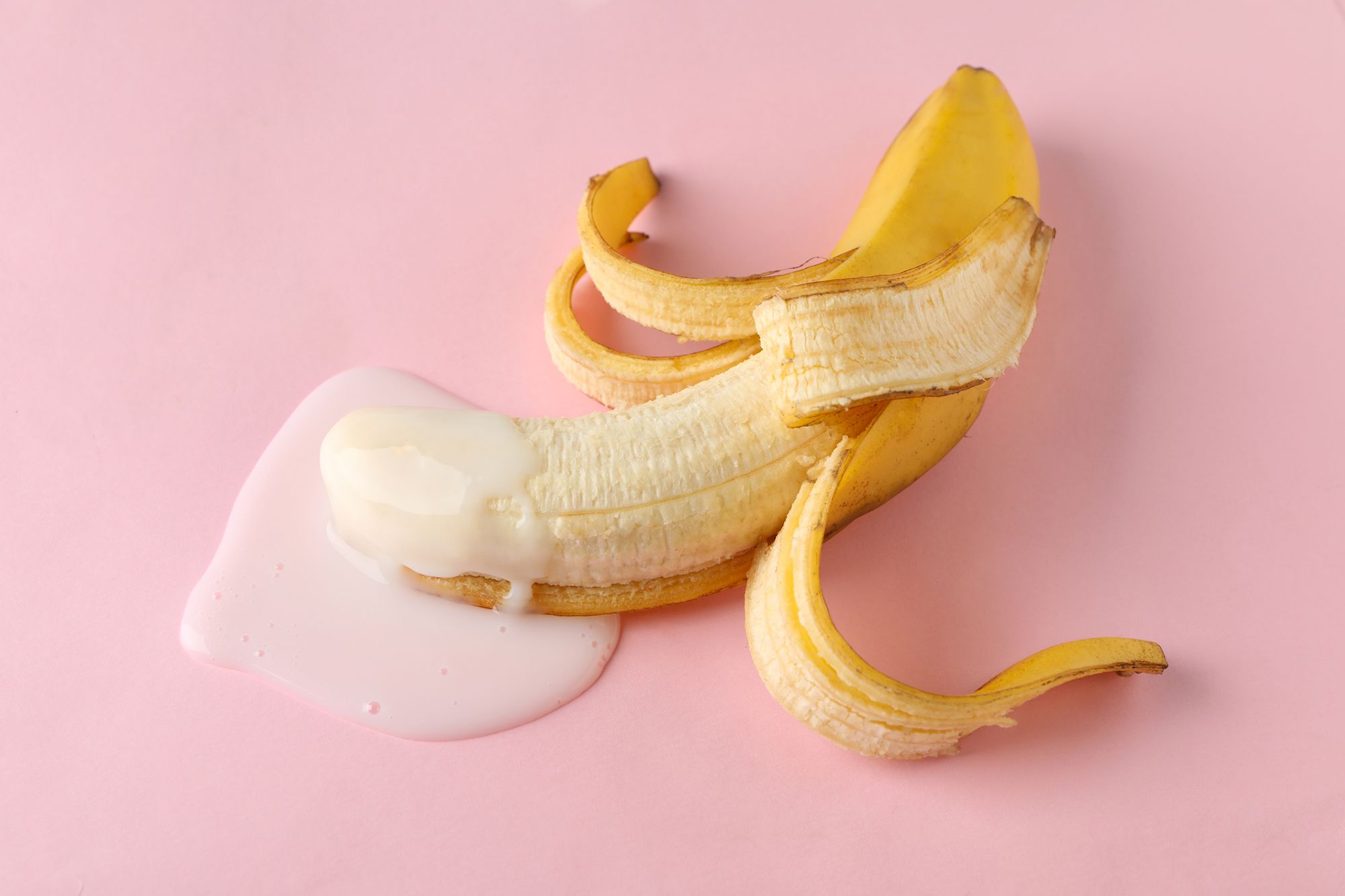 Halb geschälte Banane mit Milch auf dem vorderen Ende