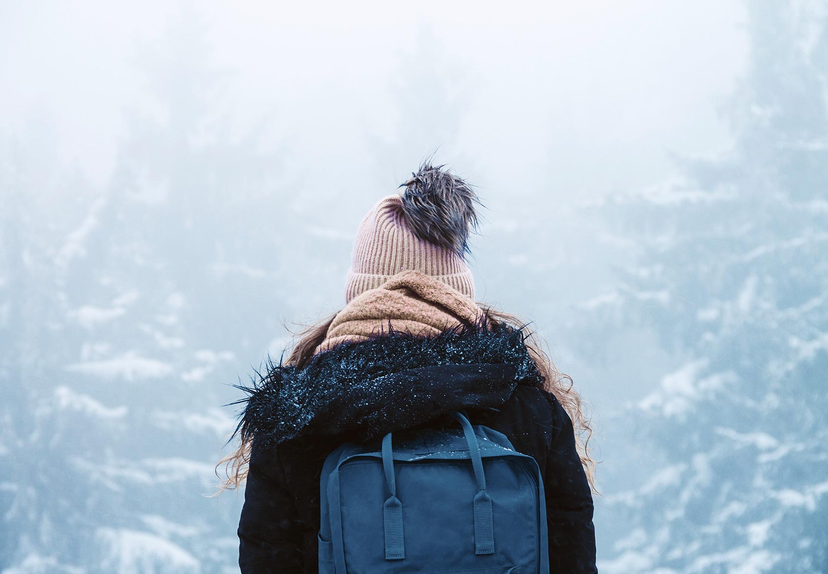 Rückansicht einer Frau in einem verschneiten Wald