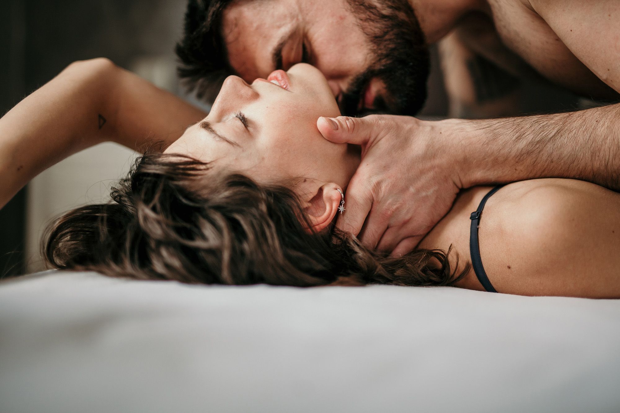 Mann und Frau im Bett, er küsst ihren Hals