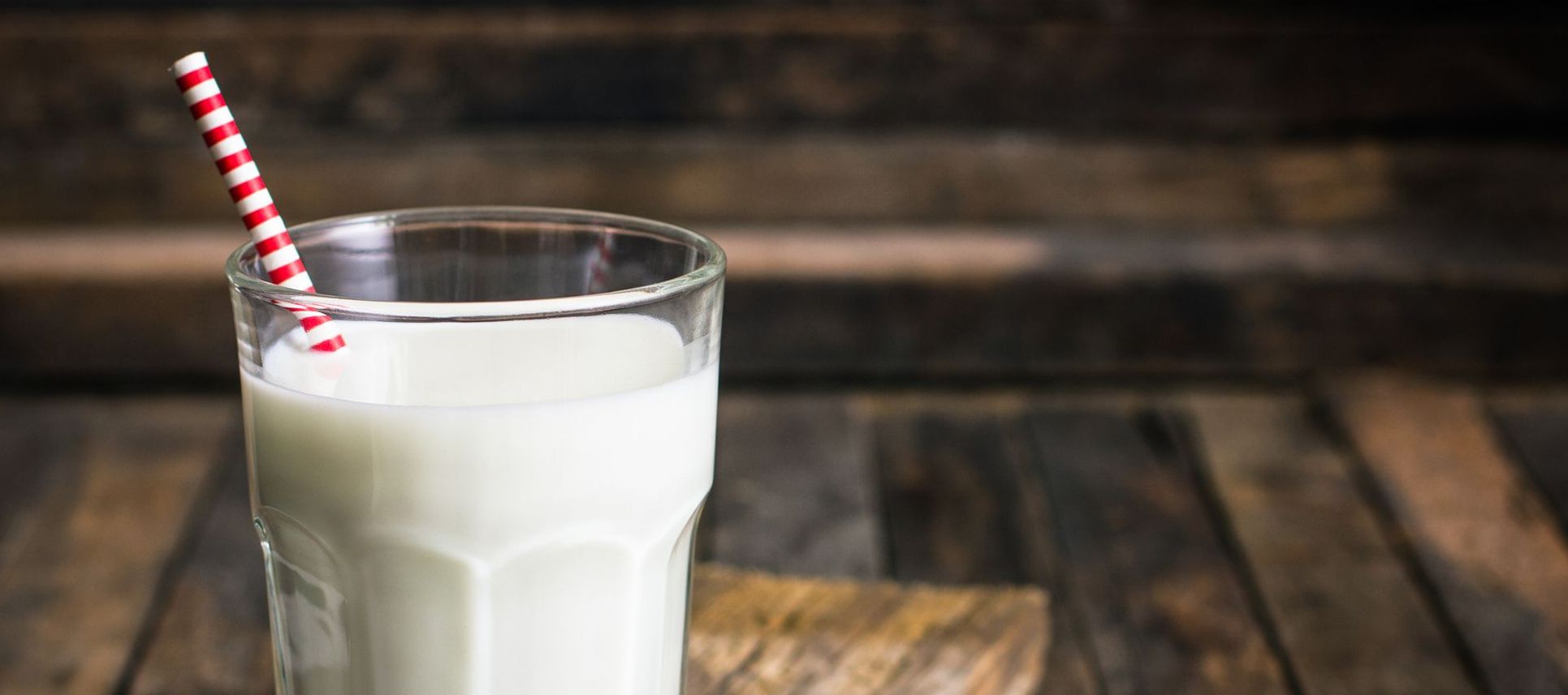 Glas voll Milch, in dem ein Strohhalm steckt