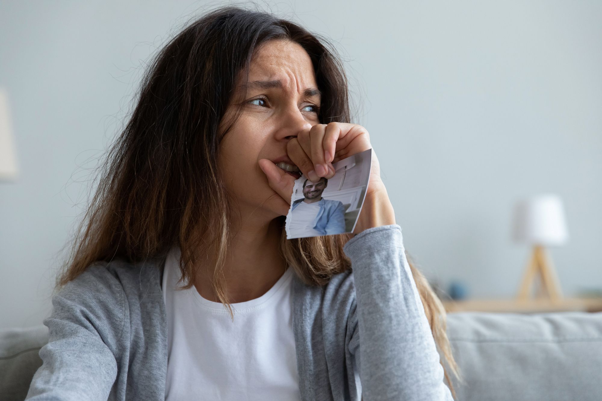 Frau schaut traurig und hält ein zerrissenes Foto in der Hand