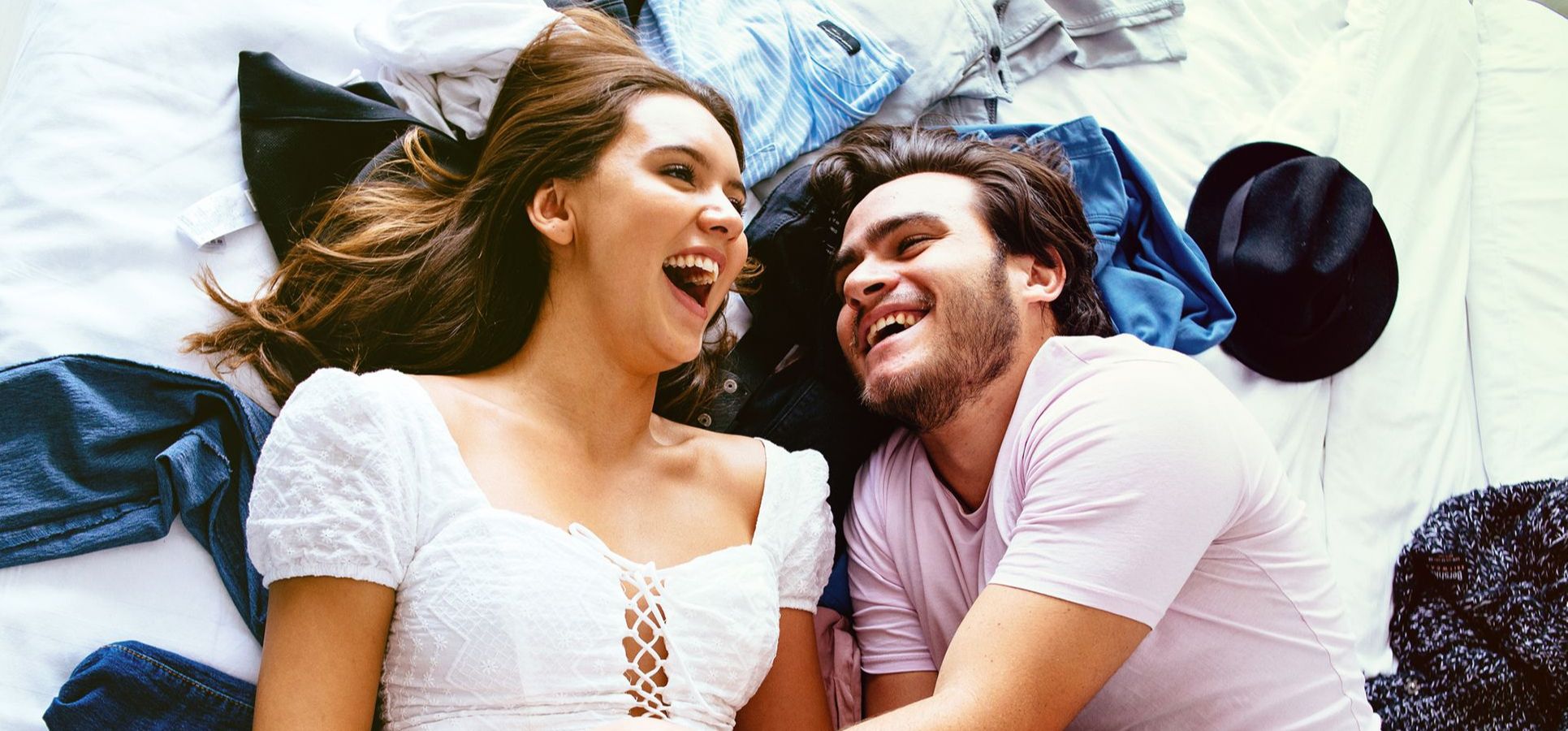 Mann umarmt Frau im Bett, beide lachen