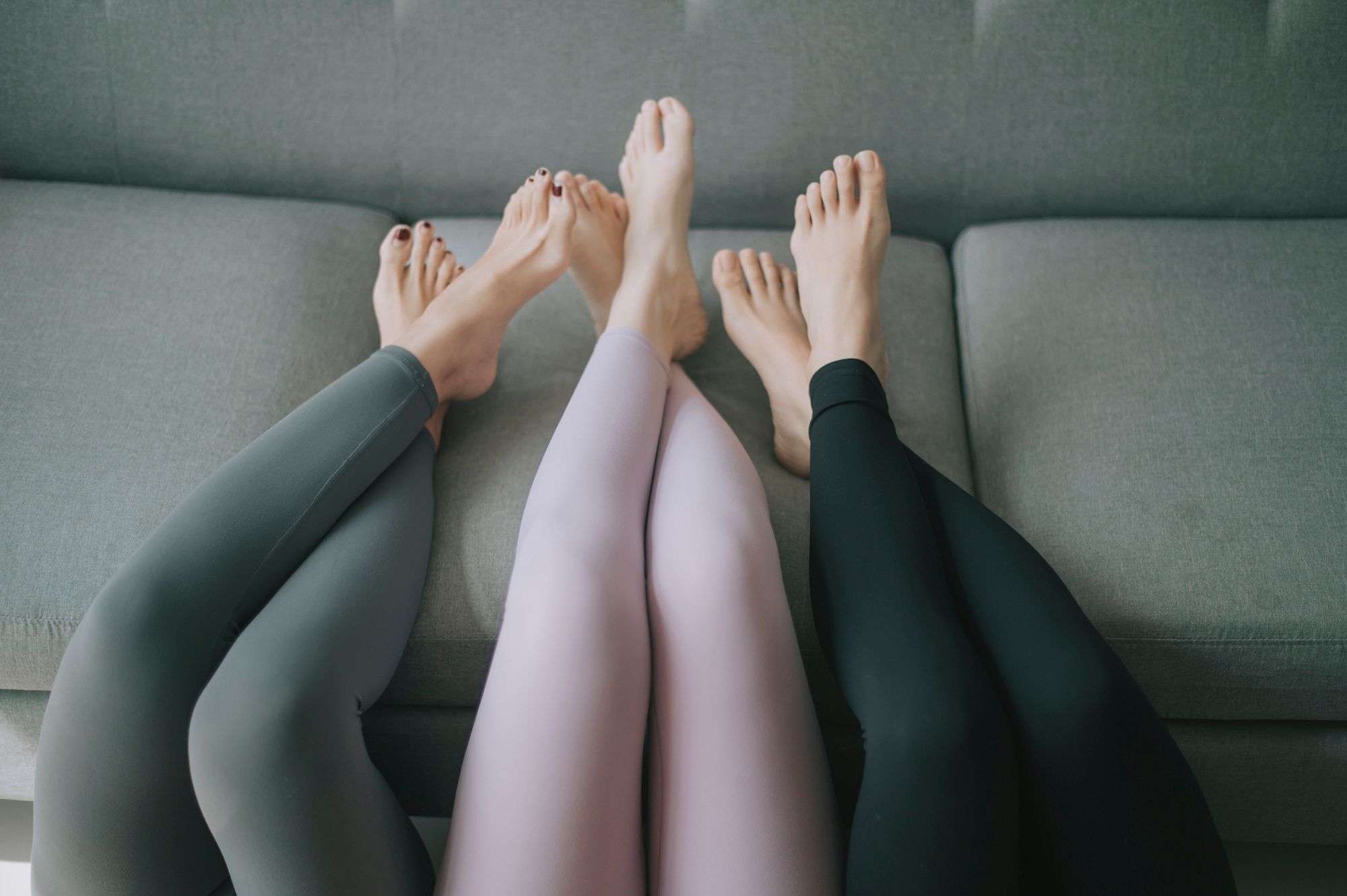 Drei Frauen, die ihre Beine mit nackten Füßen auf die Couch legen