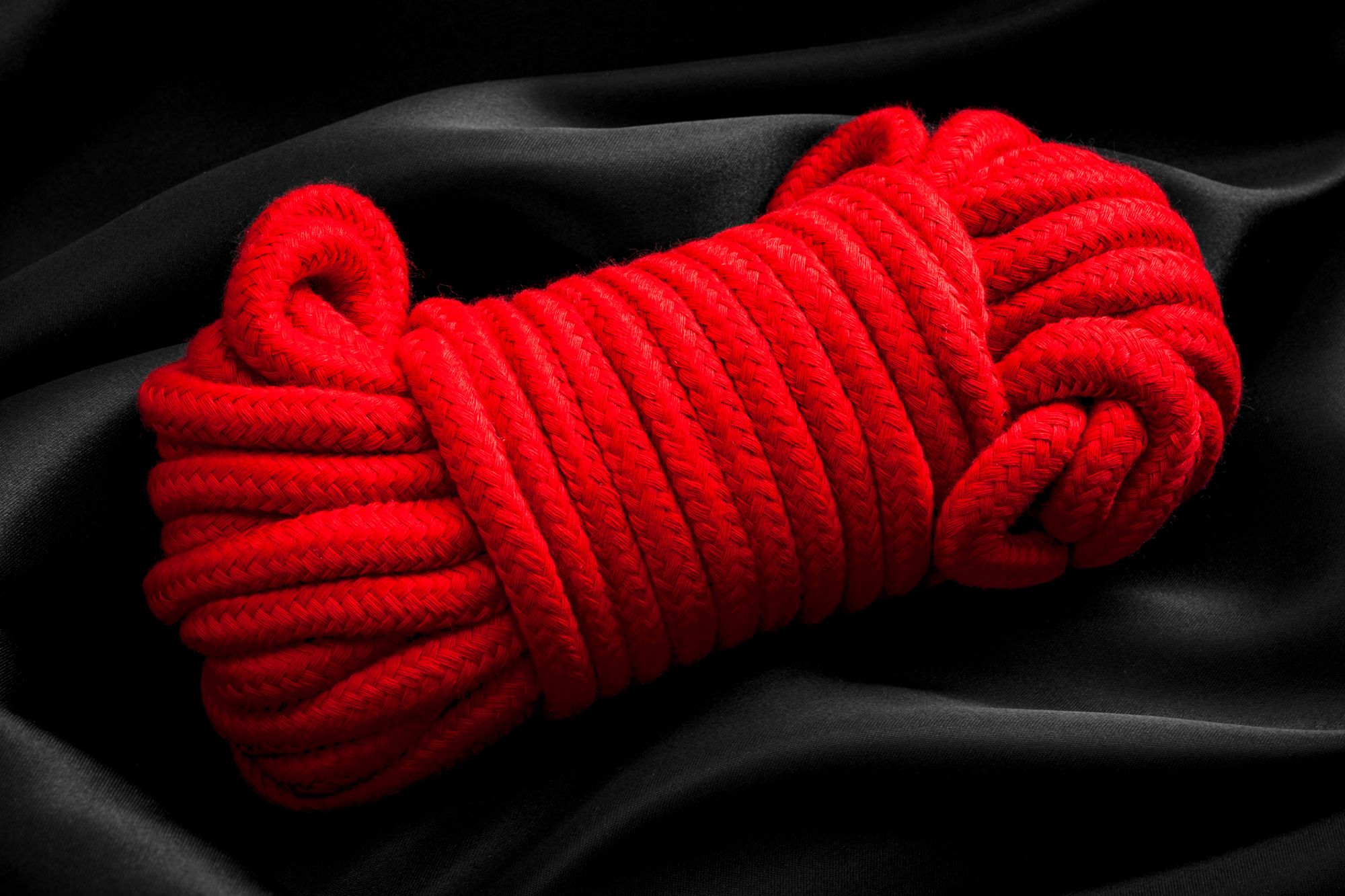 Domina Bondage - Abbildung von einem roten Seil auf einer schwarzen Decke.