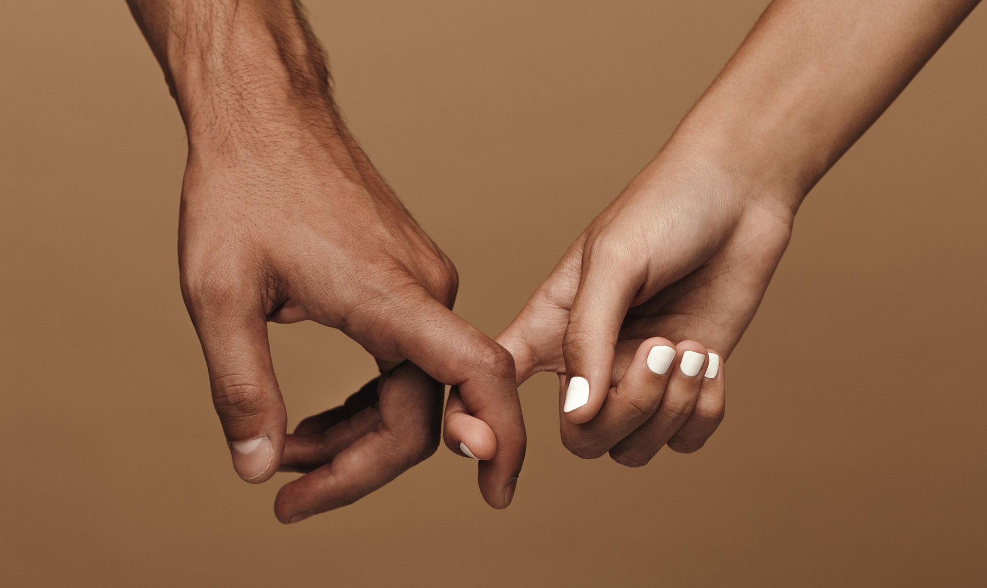 Liebeskummer ohne Beziehung - Abbildung einer männlichen und einer weiblichen Hand, die Zeigefinger sind einander eingehakt- 