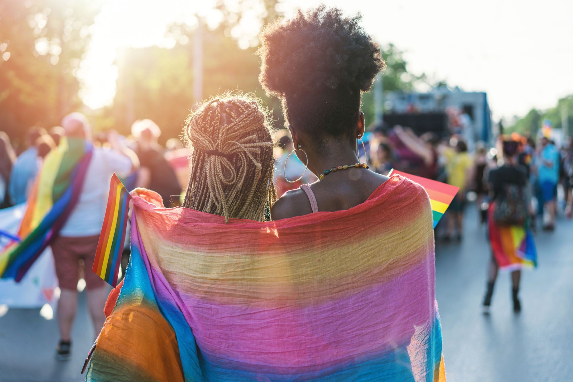 Zwei Frauen mit Regenbogenflagge um den Schultern