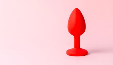 Ein roter Analdildo vor einem rosa Hintergrund