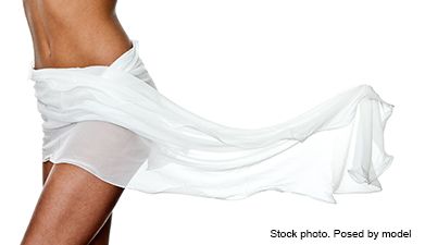 Ein Ausschnitt einer Frau, die ein weißes Laken um ihre Hüften gewickelt hat