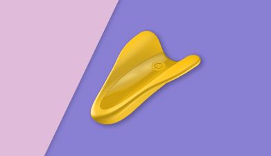 Gelber Fingervibrator Satisfyer 'High Fly' auf lila-rosa geteiltem Hintergrund