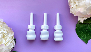 Drei kleine weiße Klistiere für die Körperpflege vor einem lilanen Hintergrund auf dem in zwei Ecken