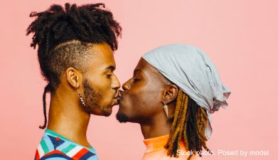 Zwei Männer die sich küssen vor einem rosa Hintergrund