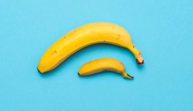 Eine kleine und eine große Banane vor einem blauen Hintergrund