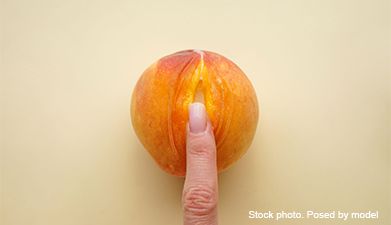 Ein Finger, der einen aufgeschnitten Pfirsich berührt