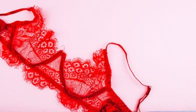 Sexy Oberteile: Roter Spitzen-BH vor einem rosa Hintergrund