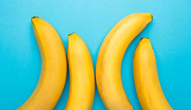 Vier Bananen die vor einem hellblauem Hintergrund liegen