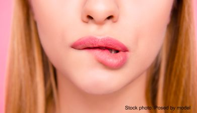 Ein Bildausschnitt einer Frau die sich auf die Lippe beißt