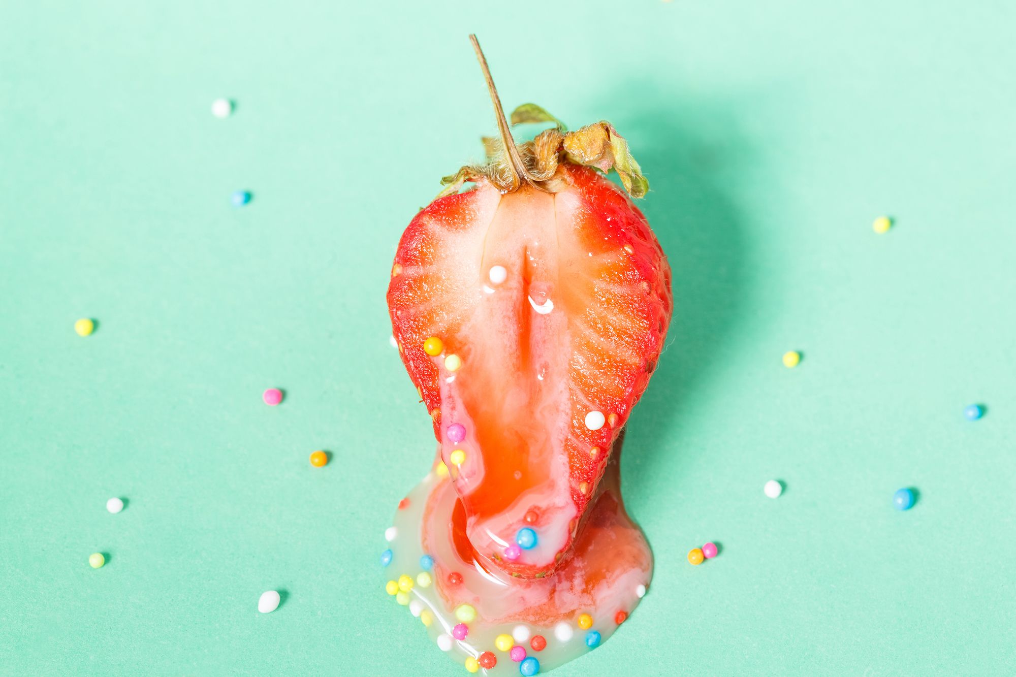 Halbierte Erdbeere mit Zuckerstreuseln, aus der eine Flüssigkeit läuft