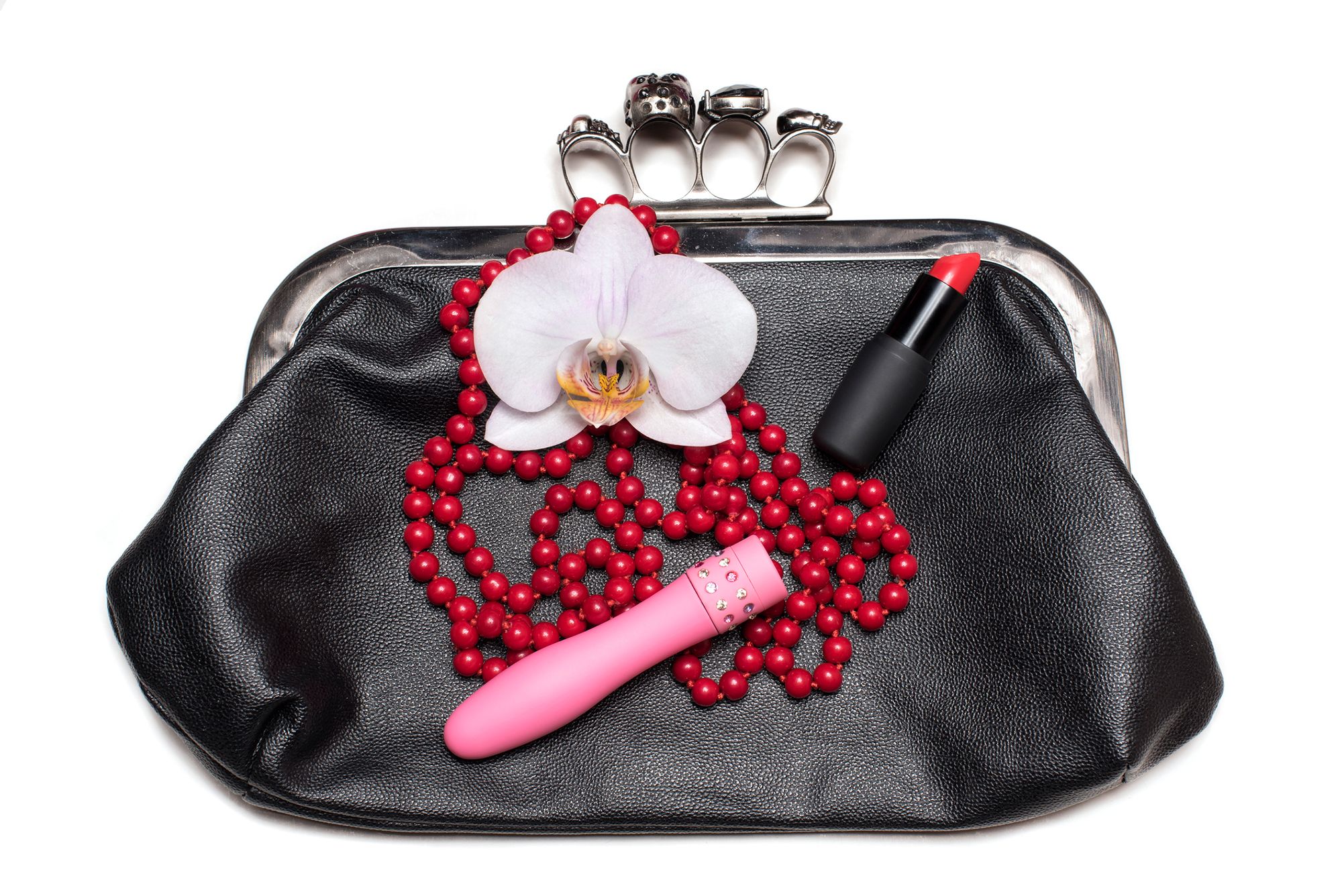 Handtasche, auf der eine Kette, ein Lippenstift und ein Vibrator liegen