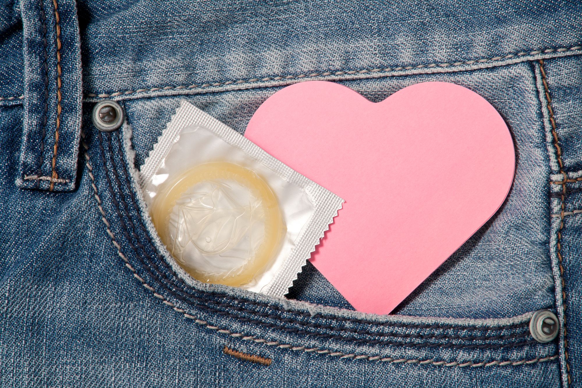 Ein Kondom und ein Herz aus Papier, die aus einer Hosentasche rausschauen