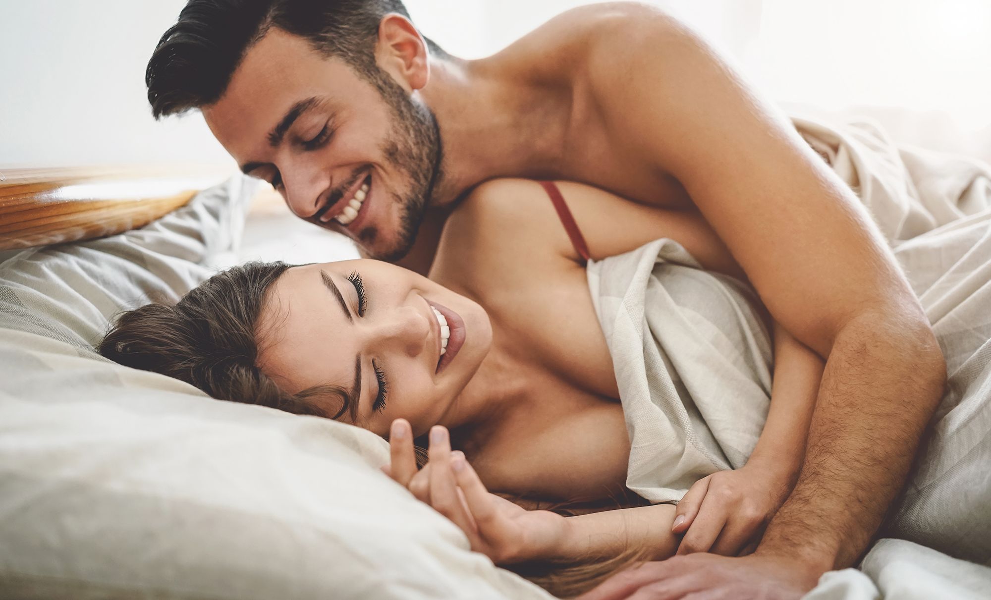 Mann kuschelt mit seiner Frau im Bett. null. 