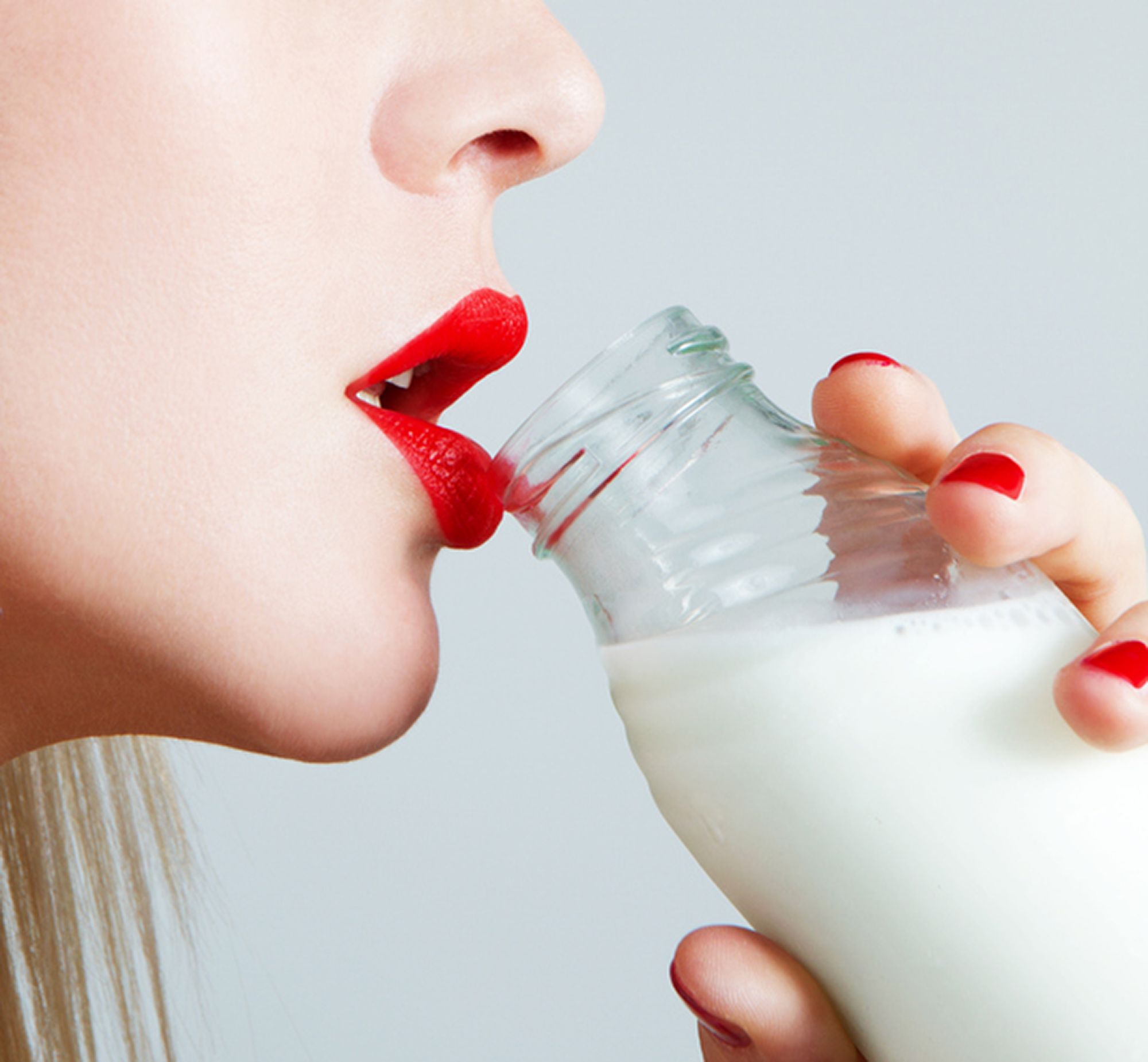 Eine Frau mit roten Lippen die Milch aus einer Flasche trinkt