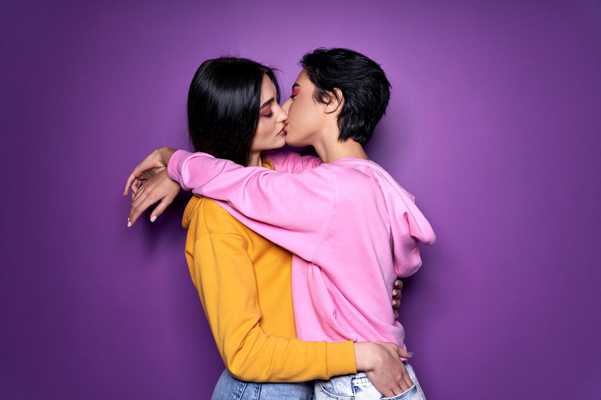 Zwei Frauen die sich küssen vor einem lila Hintegrund