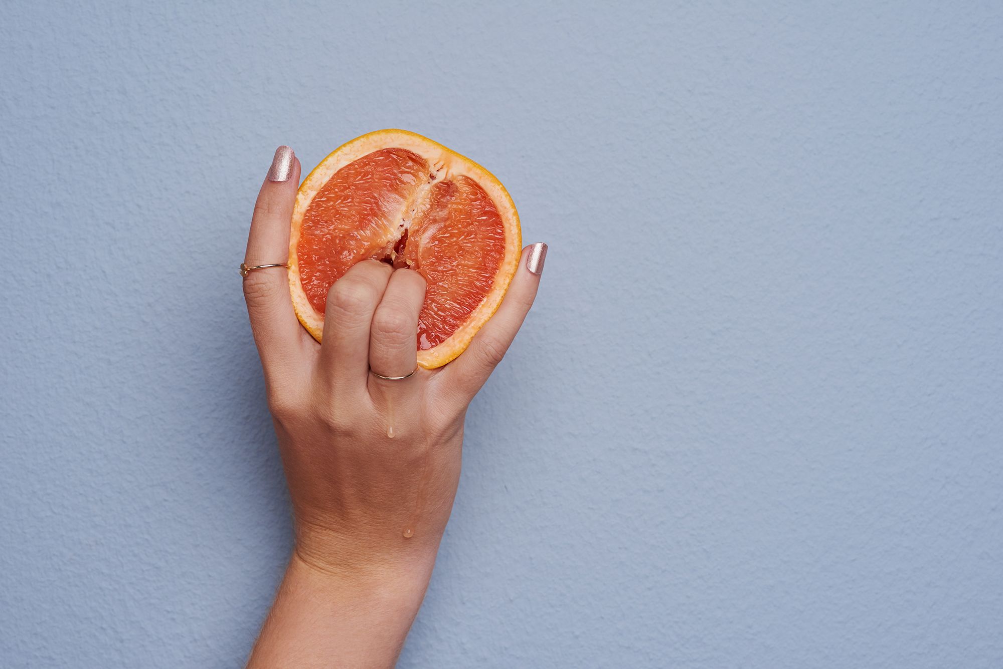 Frauenhand die mit zwei Fingern in eine Grapefruit sticht